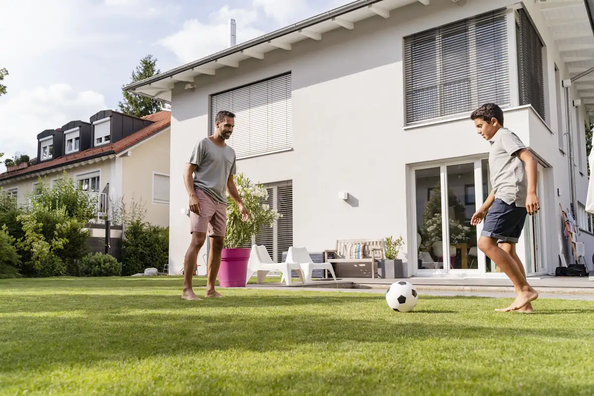 Un homme et un petit garçon qui s'amuse sur un terrain de foot maison avec un gazon naturel