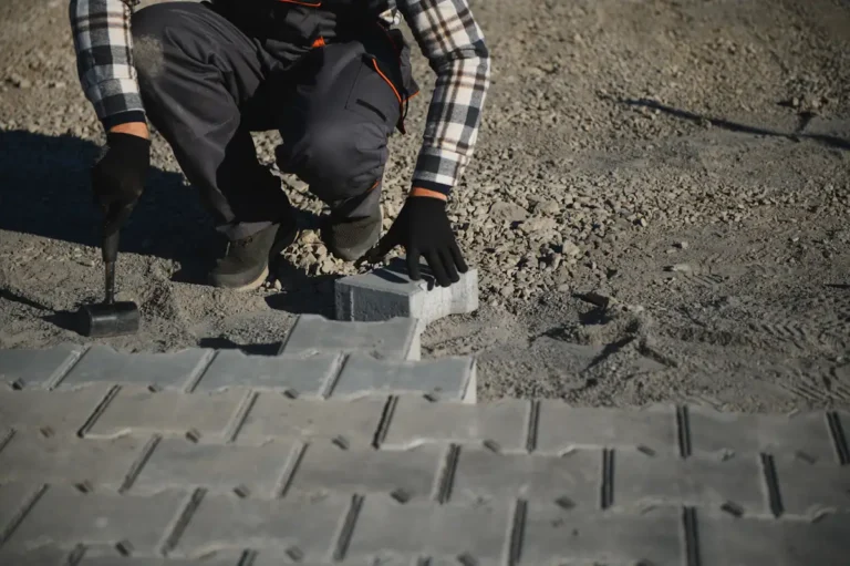 Un homme qui installe des revêtements de sol pour son parking extérieur