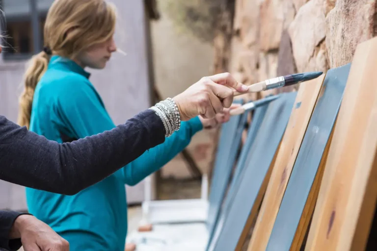 Des jeunes qui appliquent de la appliquer peinture glycéro sur du bois