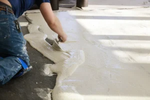 Un homme qui applique de la chape liquide sur de l'isolant
