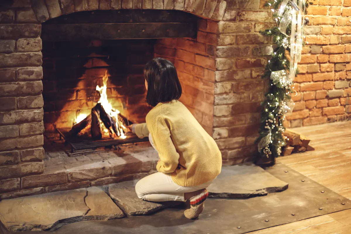 Une femme qui allume un feu dans une cheminée avec foyer