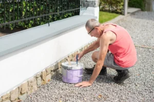 Un homme qui applique du joint pour pierre naturelle sur un mur extérieur