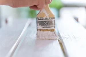 Une personne qui utilise de la peinture glycéro sur un meuble en bois