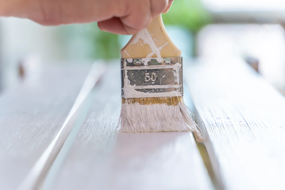 Une personne qui utilise de la peinture glycéro sur un meuble en bois