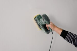 Ponçage d'une poutre en bois avant application de peinture