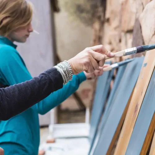 Des jeunes qui appliquent de la appliquer peinture glycéro sur du bois