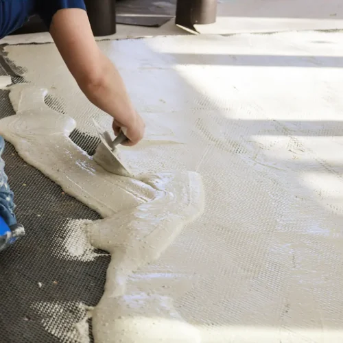 Un homme qui applique de la chape liquide sur de l'isolant