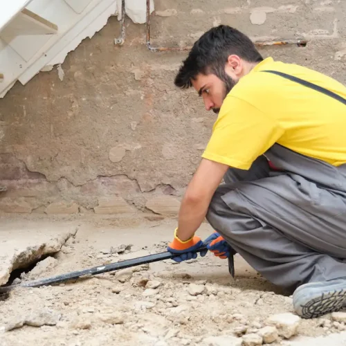 Un homme qui regarde une fissure de maison de plus près