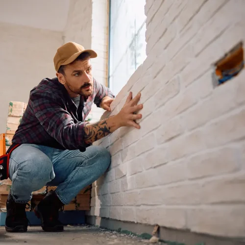 Un homme qui regarde les traces d'humidité mur en pierre intérieur