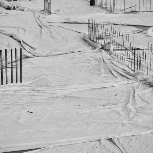 Film polyane déroulé sur hérisson de gravier avant coulage de dalle