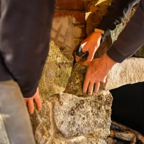 Un homme qui refait les joints d'une pierre de taille