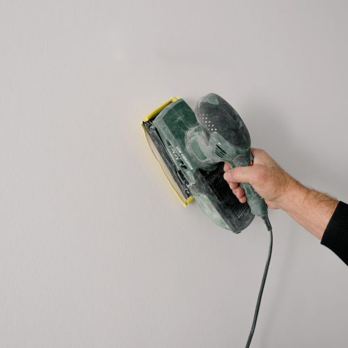 Ponçage d'une poutre en bois avant application de peinture