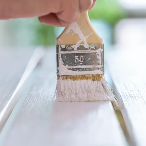 Une personne qui utilise de la peinture glycéro sur un meuble en bois